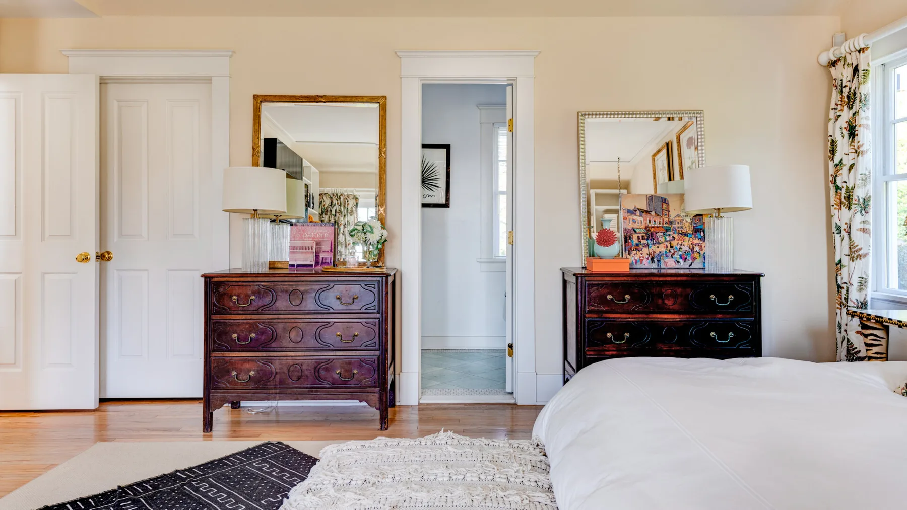 Un dormitorio luminoso con una cama, cómodas y ventanas a lo largo de una pared.