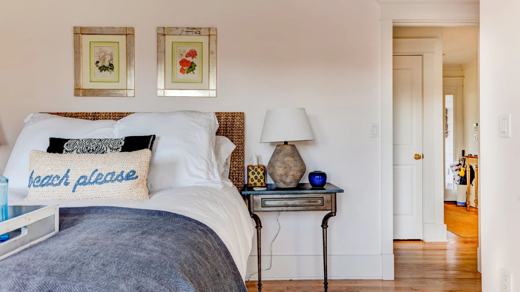 Un dormitorio con una cama bien arreglada y cuadros enmarcados encima.