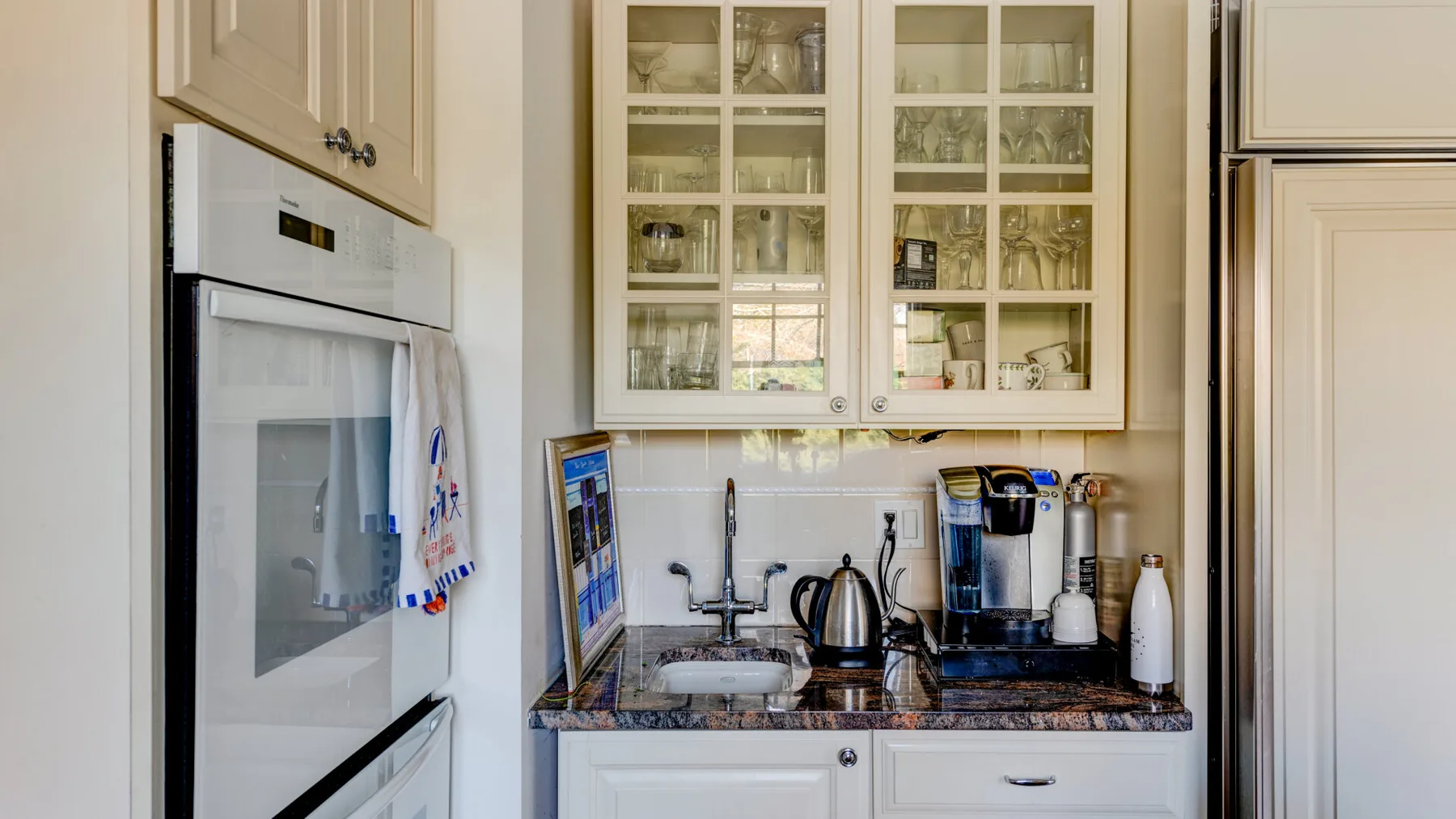 Una cocina luminosa con gabinetes blancos, una encimera y electrodomésticos.
