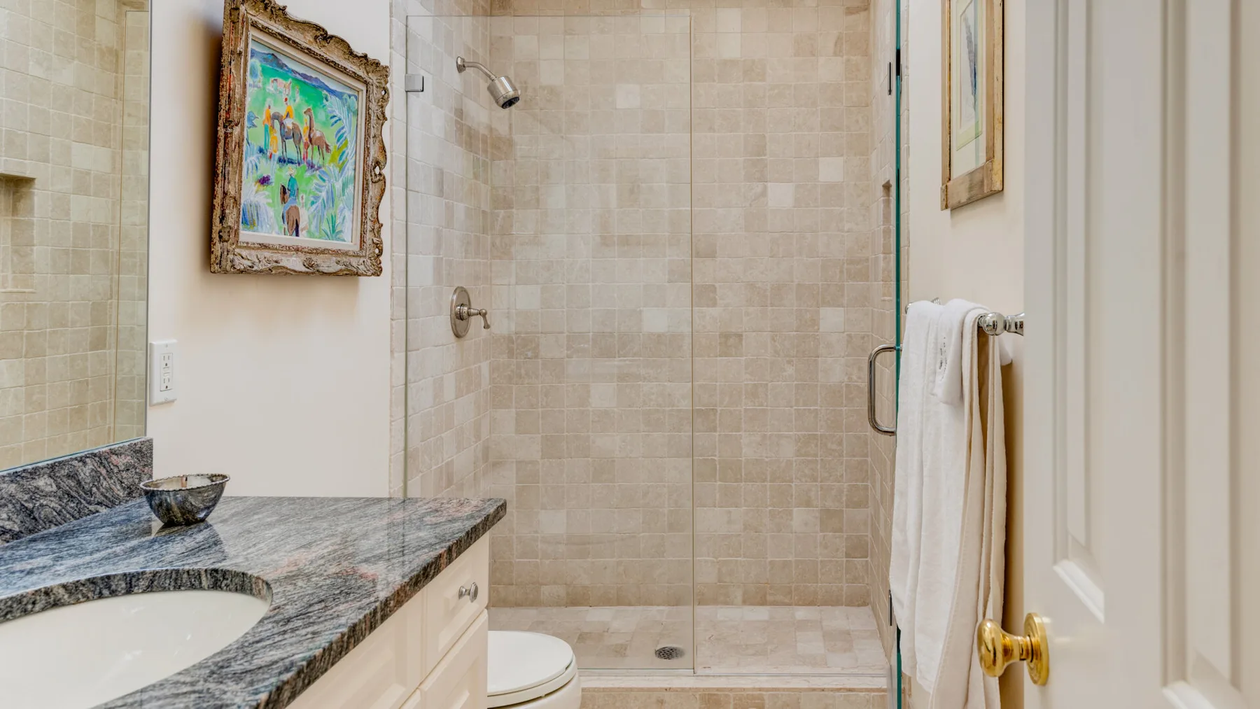 Un baño alicatado con una ducha de vidrio y un lavabo de piedra.