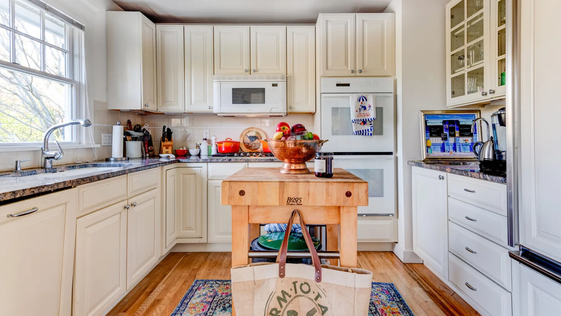 Una cocina luminosa con gabinetes blancos, una isla central y una ventana grande.