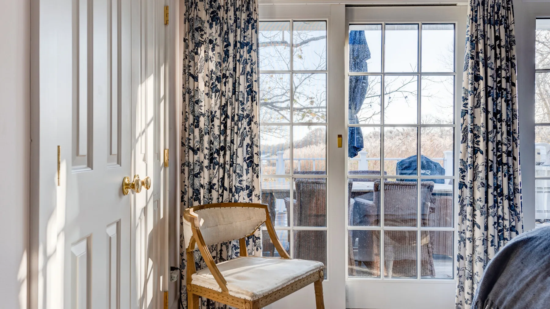 Una habitación luminosa con puertas de vidrio hacia un balcón y cortinas estampadas.