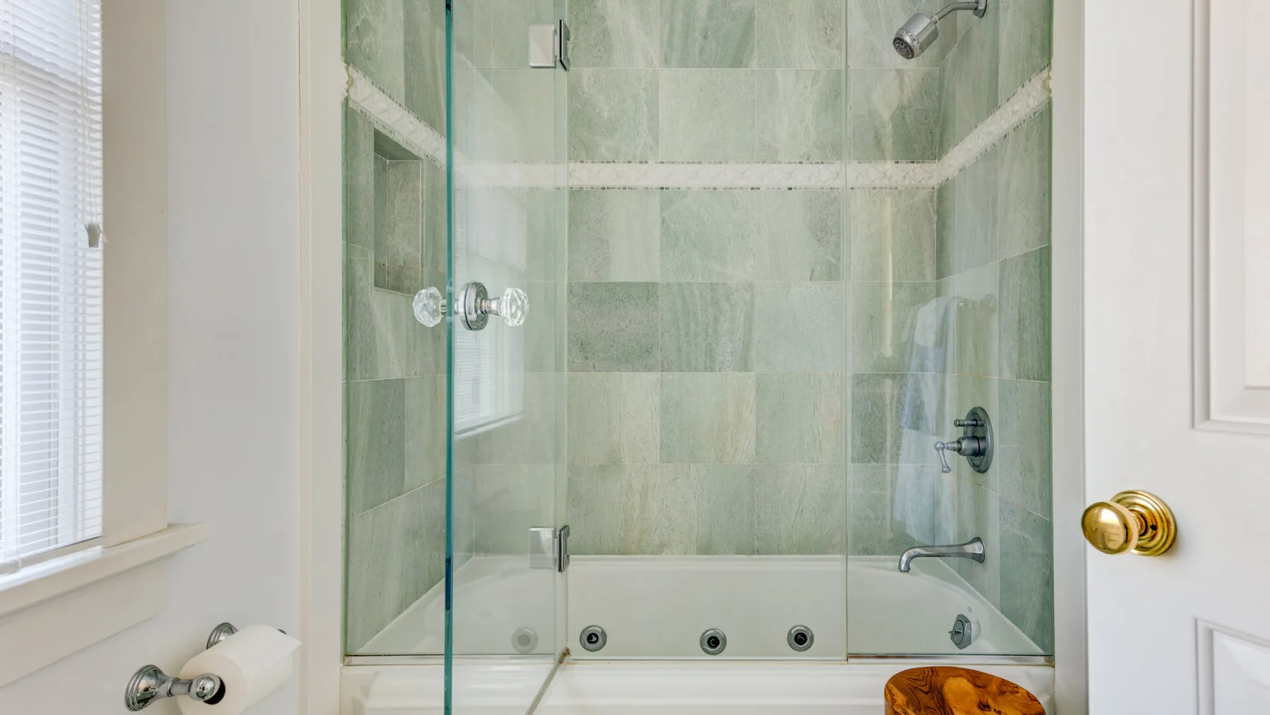 Una ducha de azulejos con paneles de vidrio y accesorios metálicos.