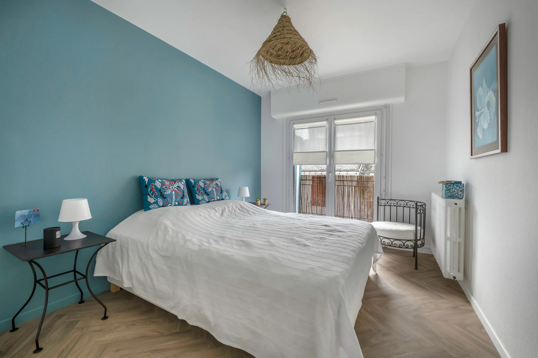 Dormitorio con una cama grande, una pared azul y puertas de cristal.