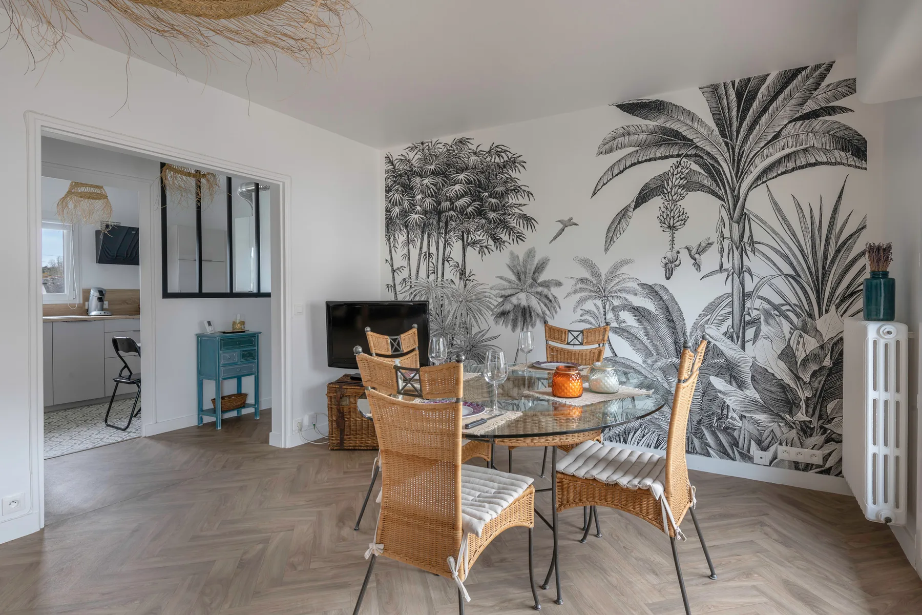 Comedor con asientos de mimbre y un gran mural botánico en la pared.