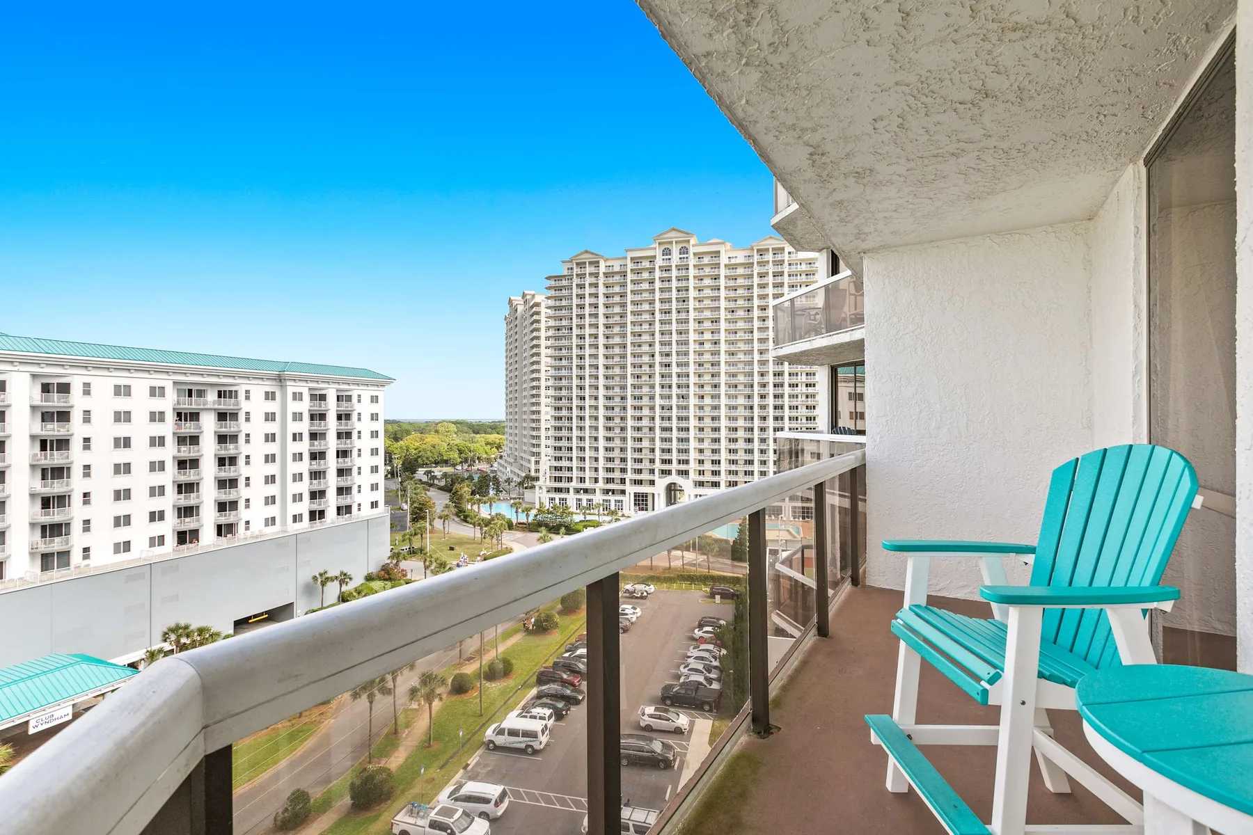 A balcony overlooks nearby buildings and a street, with turquoise seating.