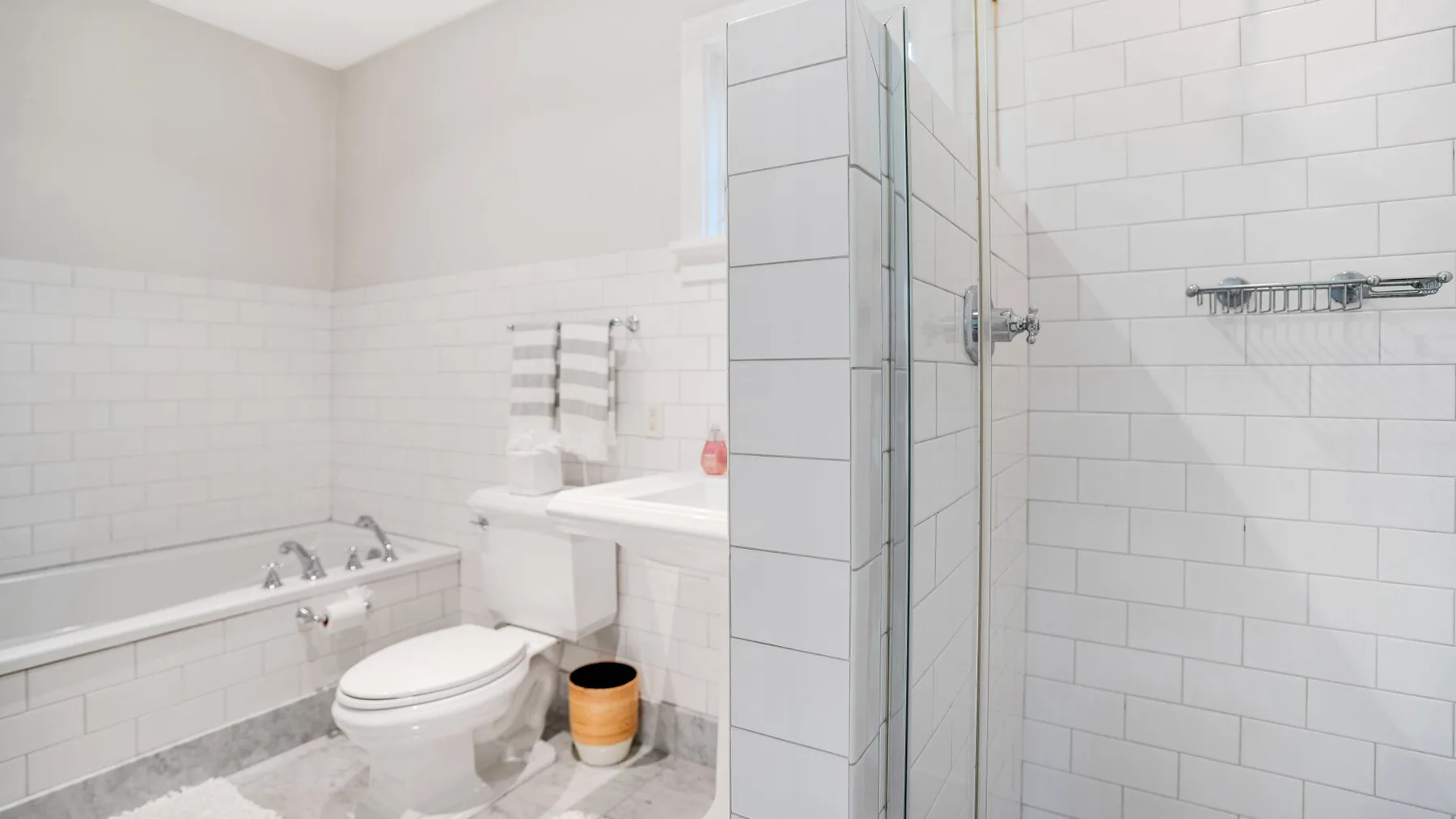 A tiled bathroom with a bathtub, toilet, and glass shower.