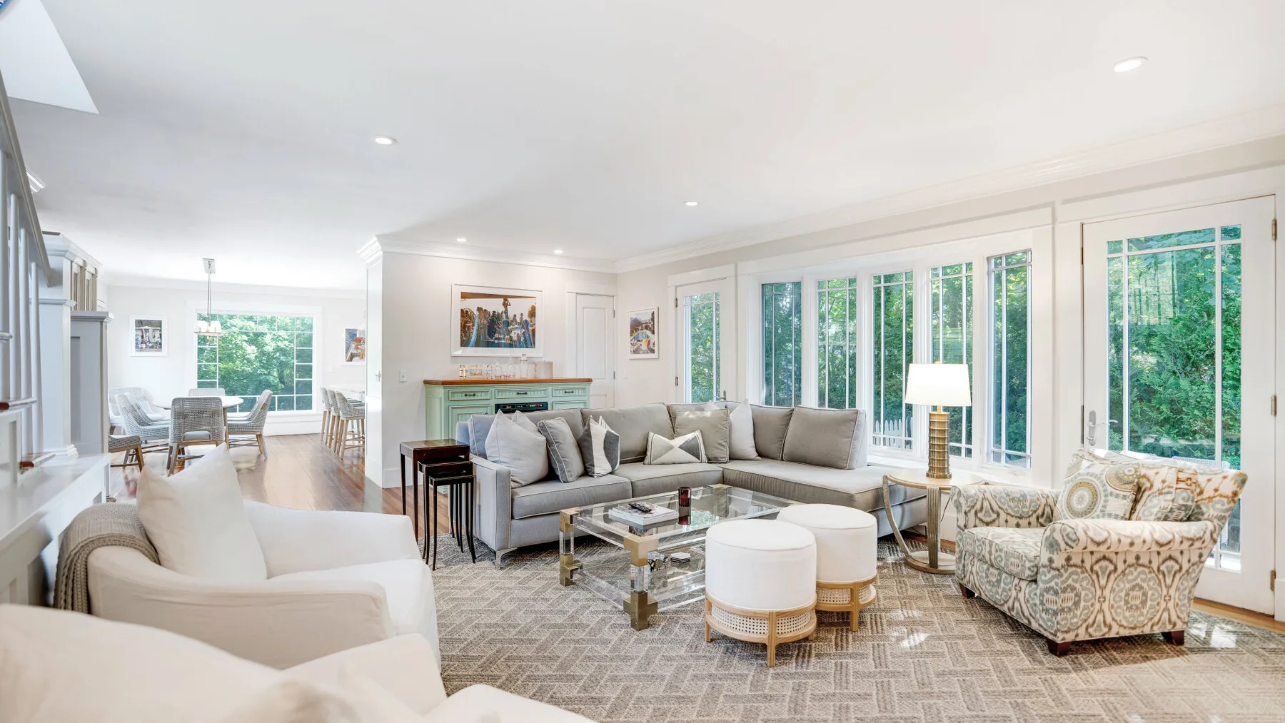 A bright living room with seating arranged around a coffee table and large windows.