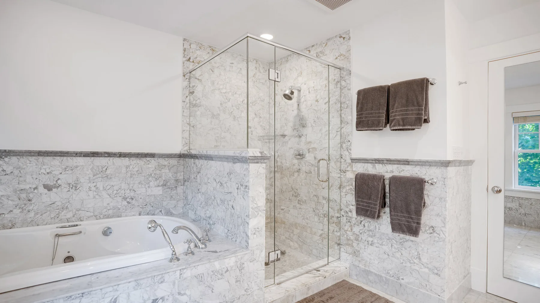A bright bathroom with a glass-enclosed shower and a bathtub.