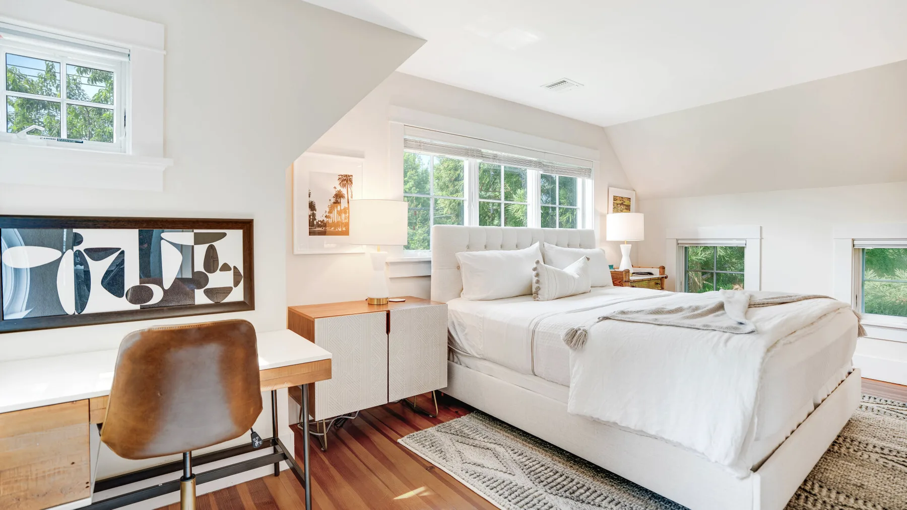 A bright bedroom with a large bed and a desk beside the window.