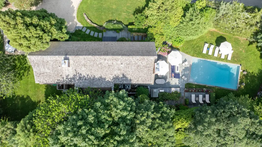 An aerial view shows a long building beside a swimming pool and landscaped grounds.