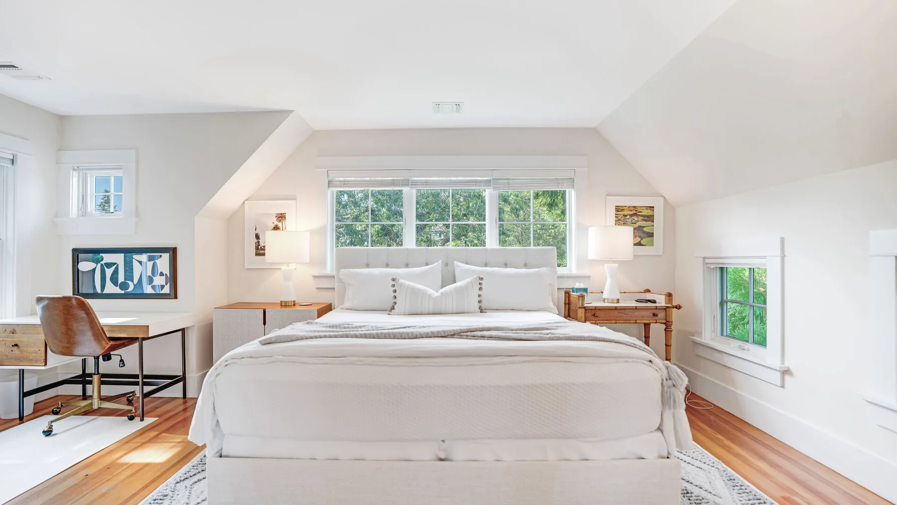 A bright bedroom with a large bed beneath a wide window.