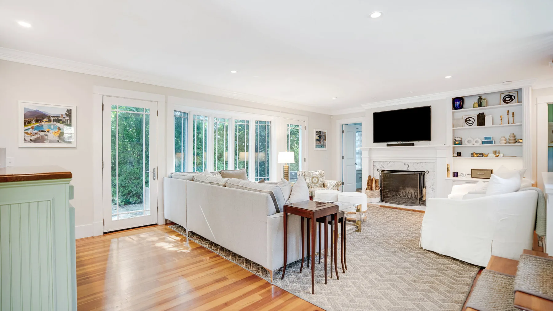A bright living room with seating, a television, and large windows.
