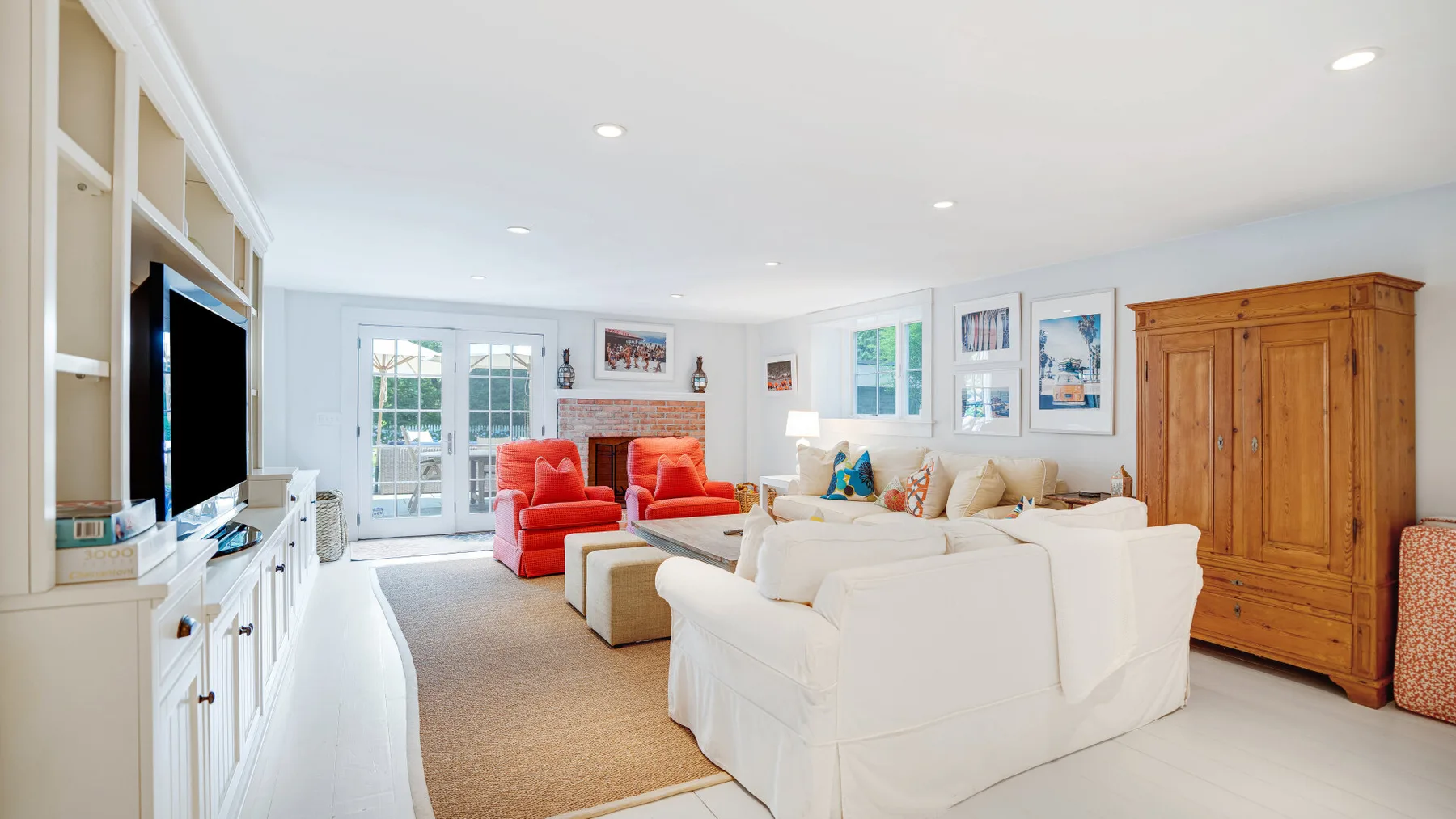 A bright living room with white seating arranged around a rug.