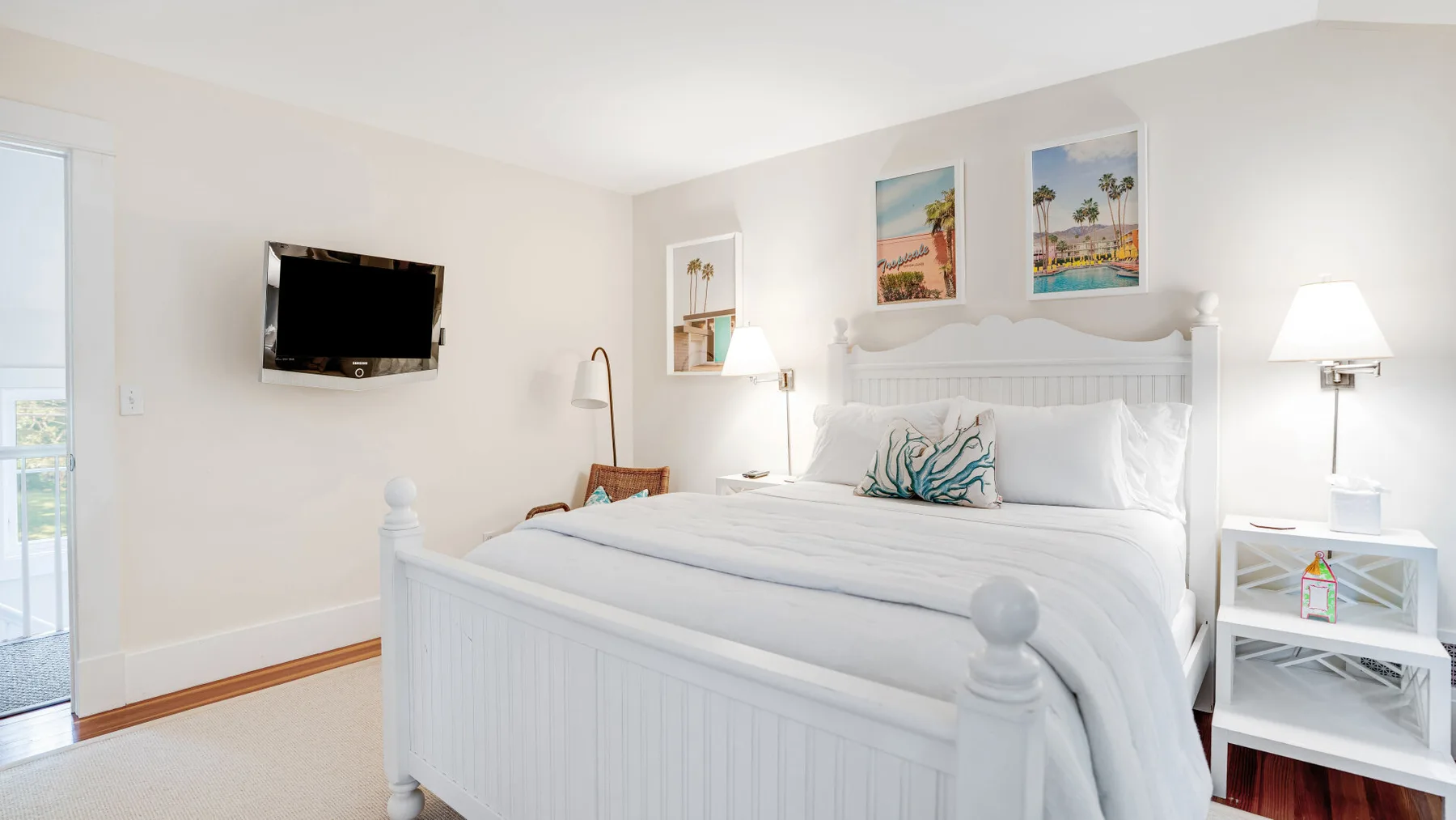 A bright bedroom with a large bed, wall-mounted television, and bedside tables.