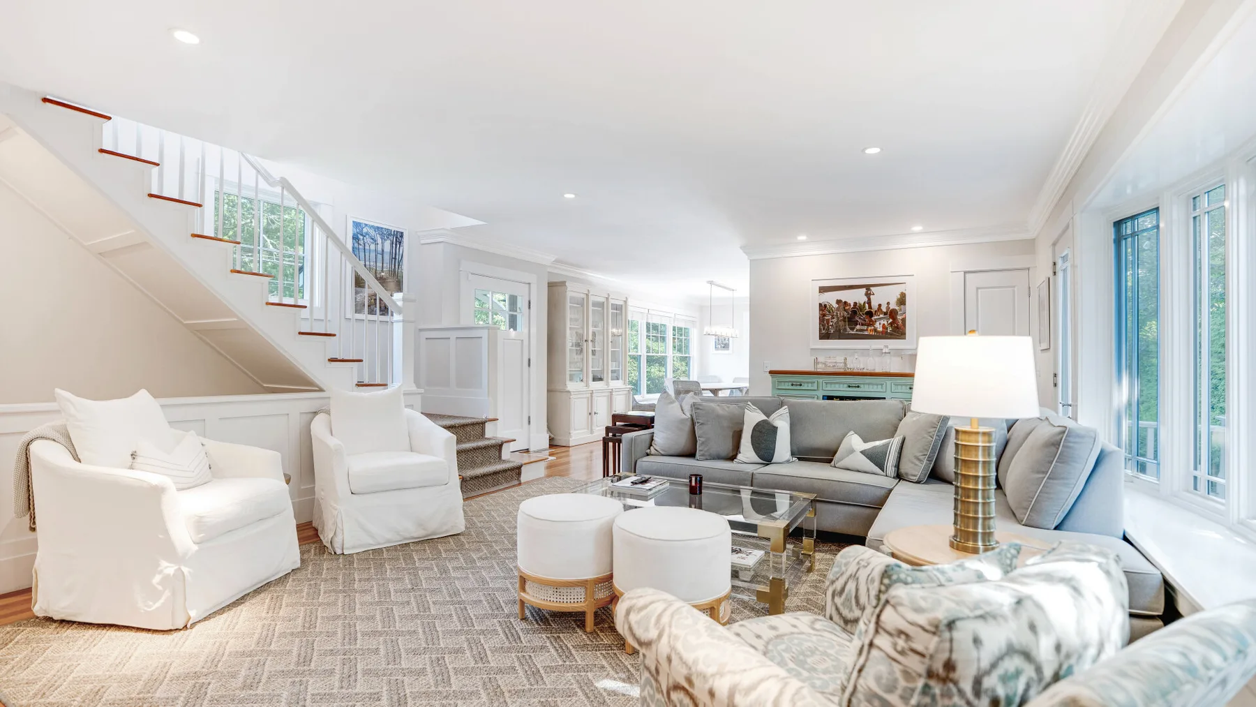 A bright living room with sofas and armchairs arranged around a coffee table.