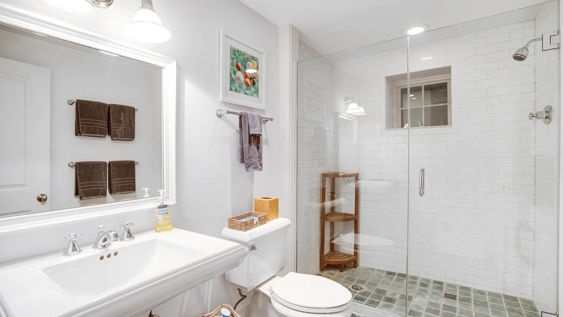 A bright bathroom with a vanity, mirror, and glass-enclosed shower.