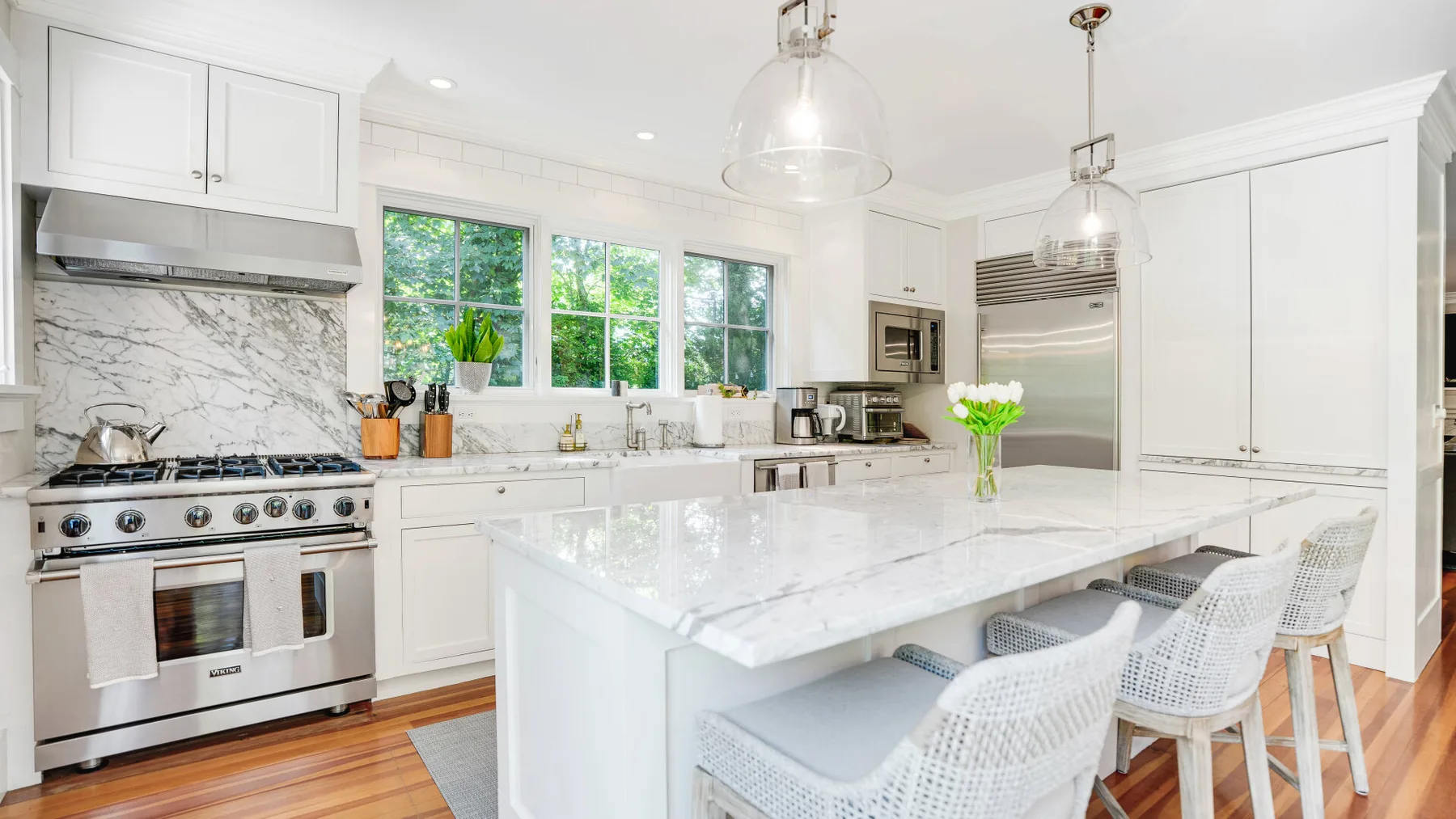 A bright kitchen with white cabinetry, a large island, and pendant lights.