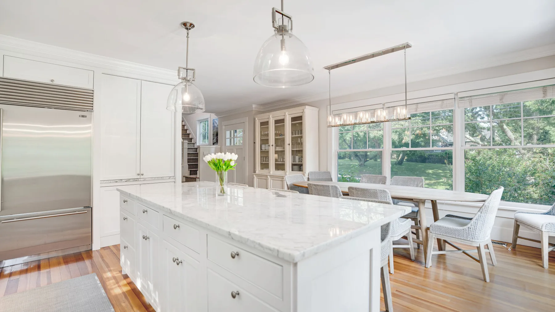 A bright kitchen with a large island and a dining table beside wide windows.