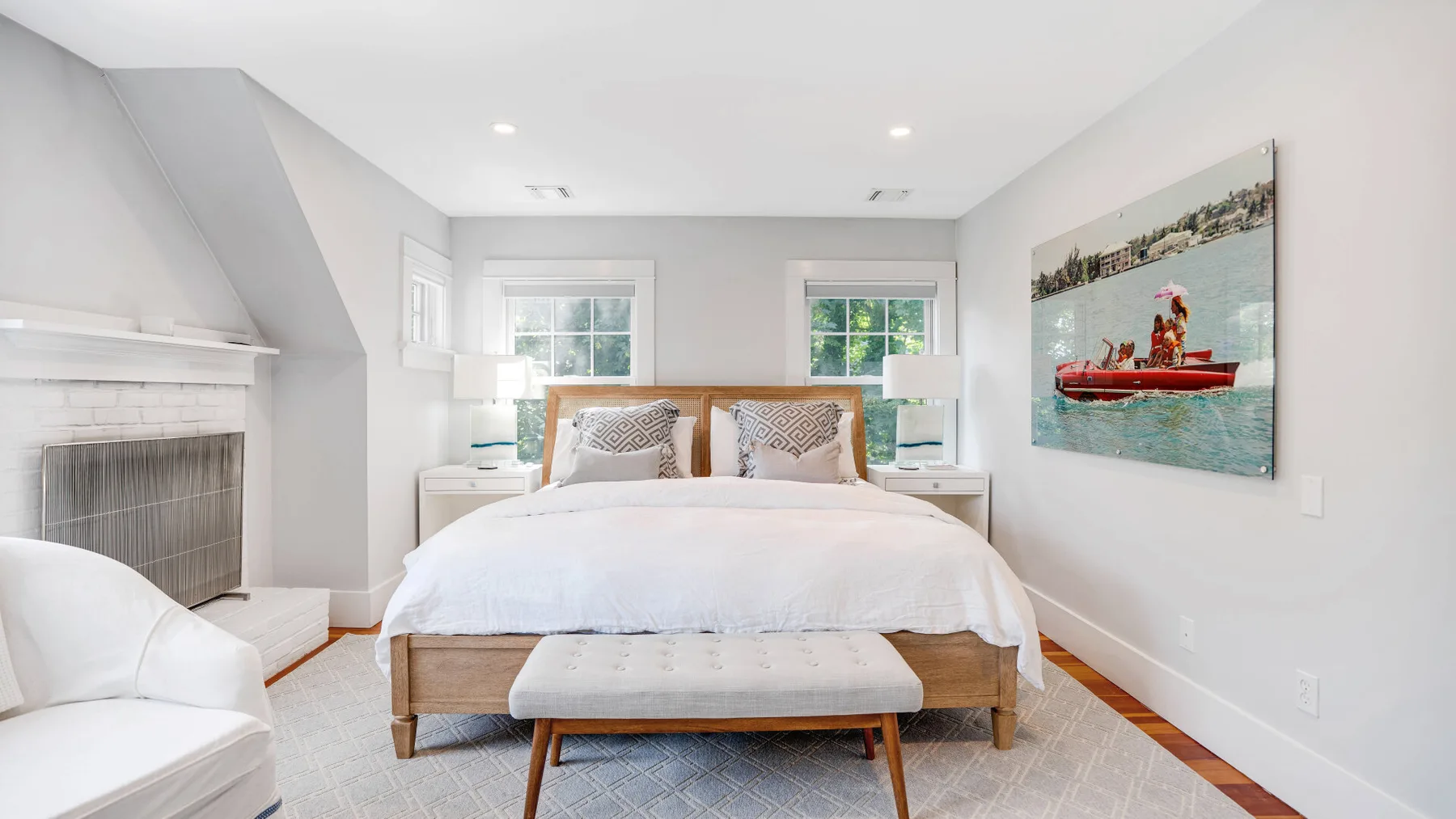 A bright bedroom with a large bed and a colorful boat painting.