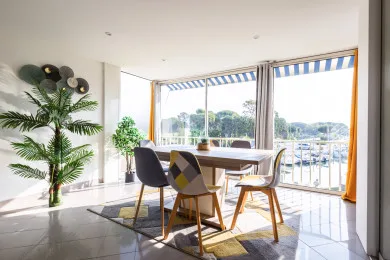 A bright dining area with a table and chairs beside large windows.