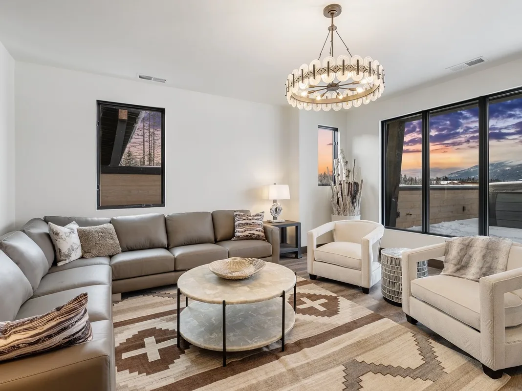A bright living room with seating around a coffee table and large windows.