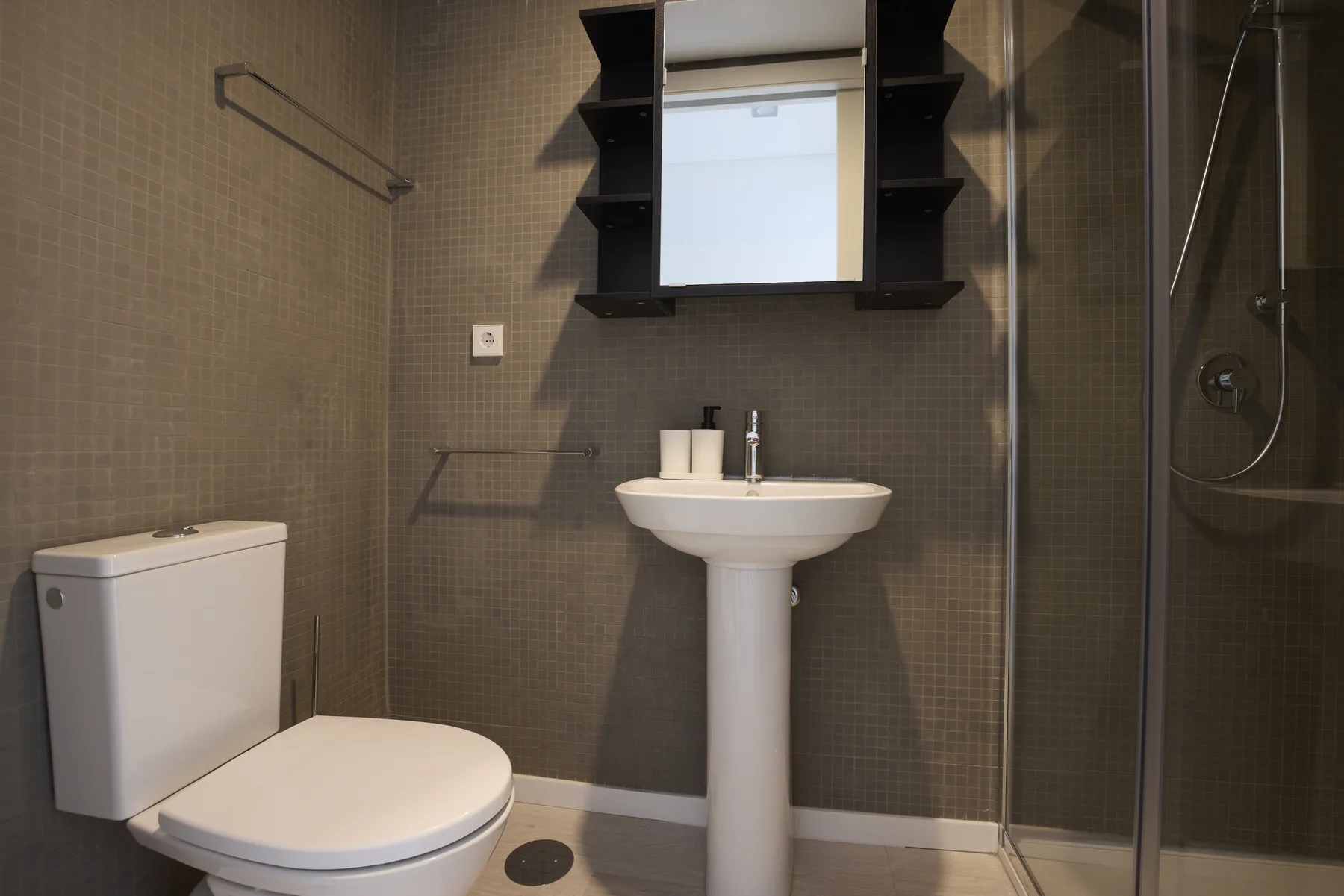 A tiled bathroom with a pedestal sink, toilet, and shower.