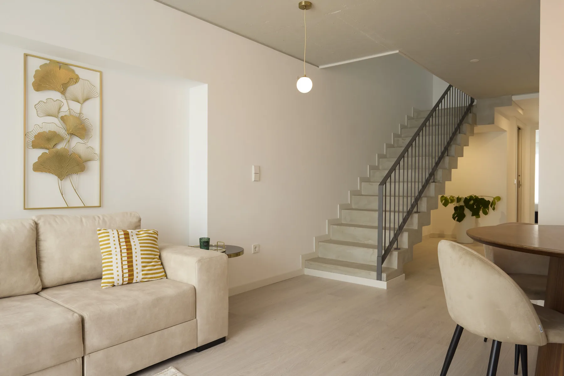 A bright living area with seating beside a staircase and dining table.
