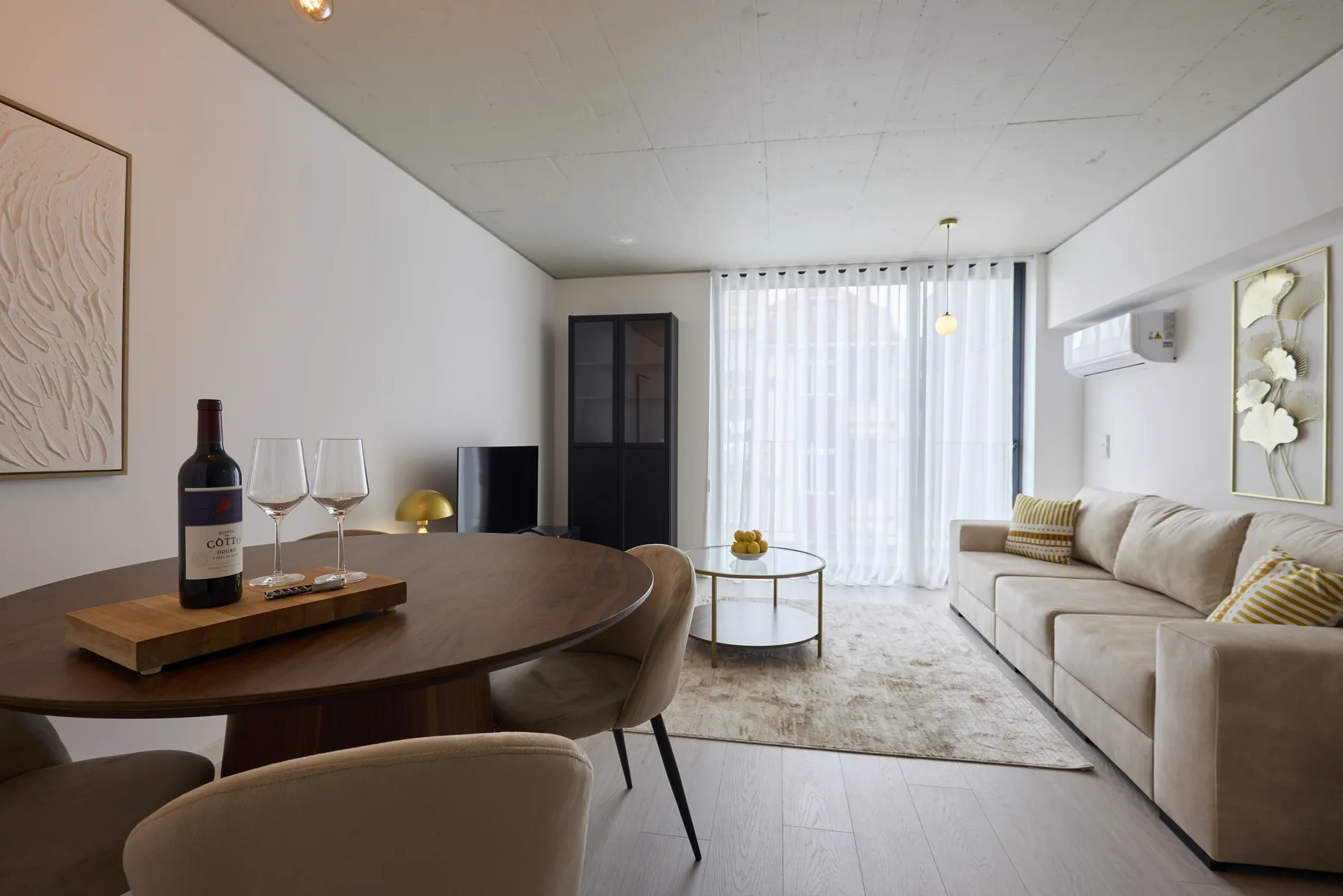 A bright living room with a dining table, seating, and a large curtained window.