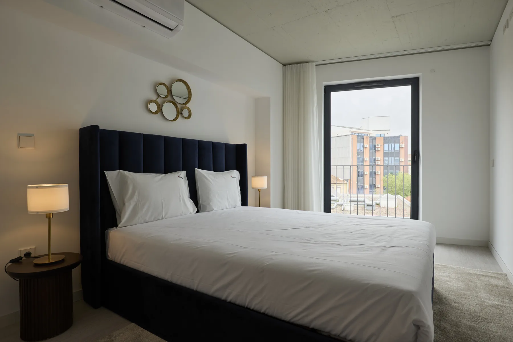 A bedroom with a neatly made bed beside a large window.