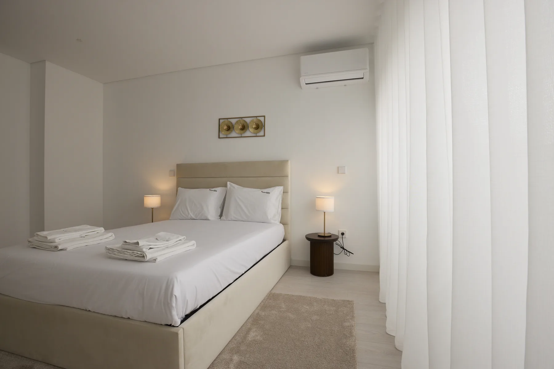A bedroom with a neatly made bed and bedside lamps.
