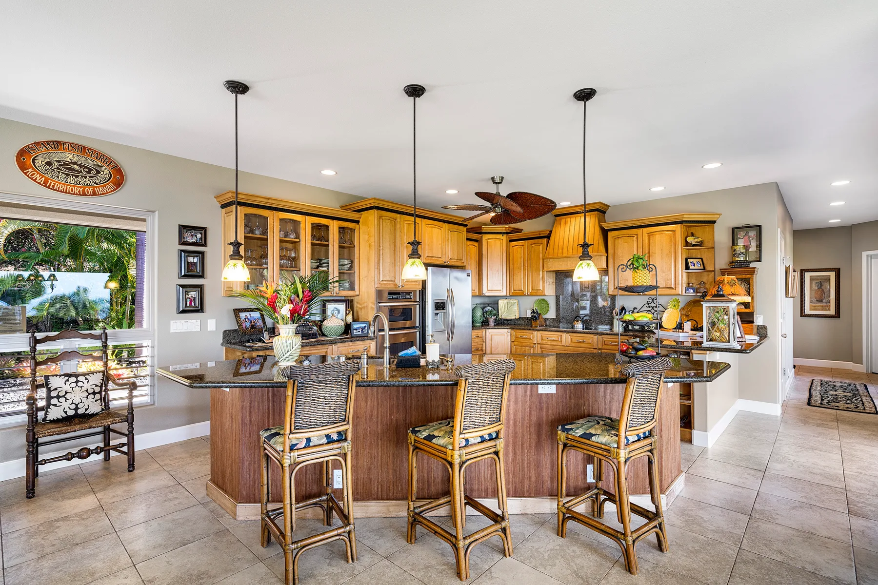 A spacious kitchen with wooden cabinetry, a central island, and bar seating.