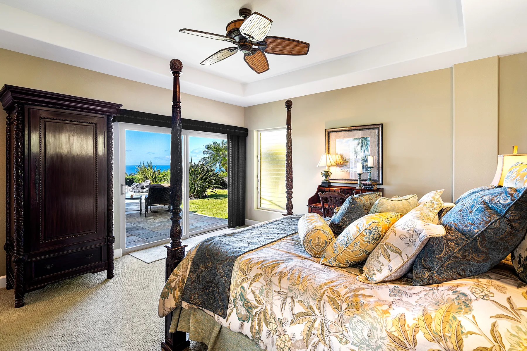 A bedroom with a canopy bed, bedside table, and glass doors opening to a patio.