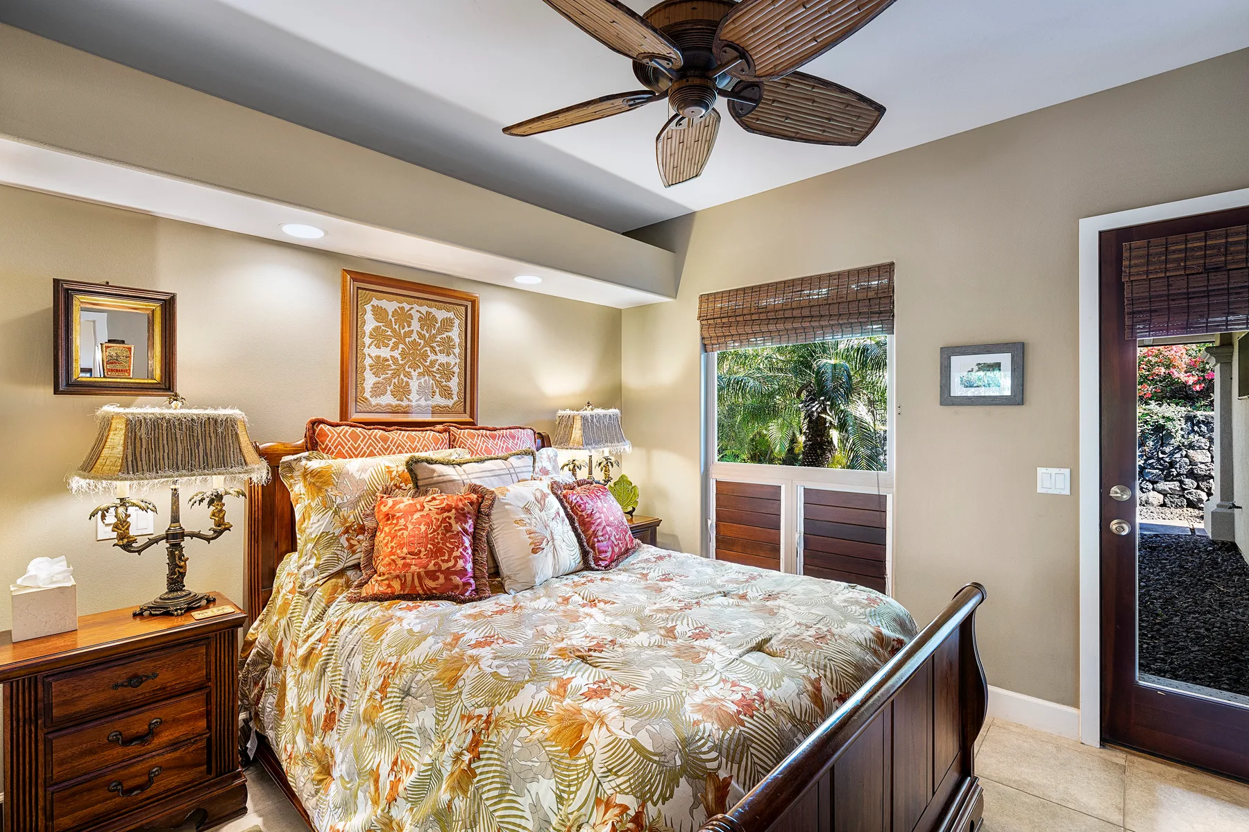 A bedroom with a bed, bedside tables, and windows overlooking greenery.