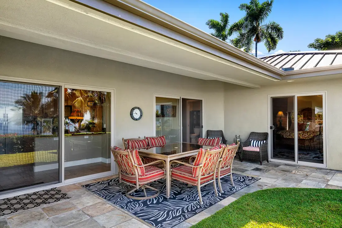 Patio dining area with a table and cushioned seating beside the house.