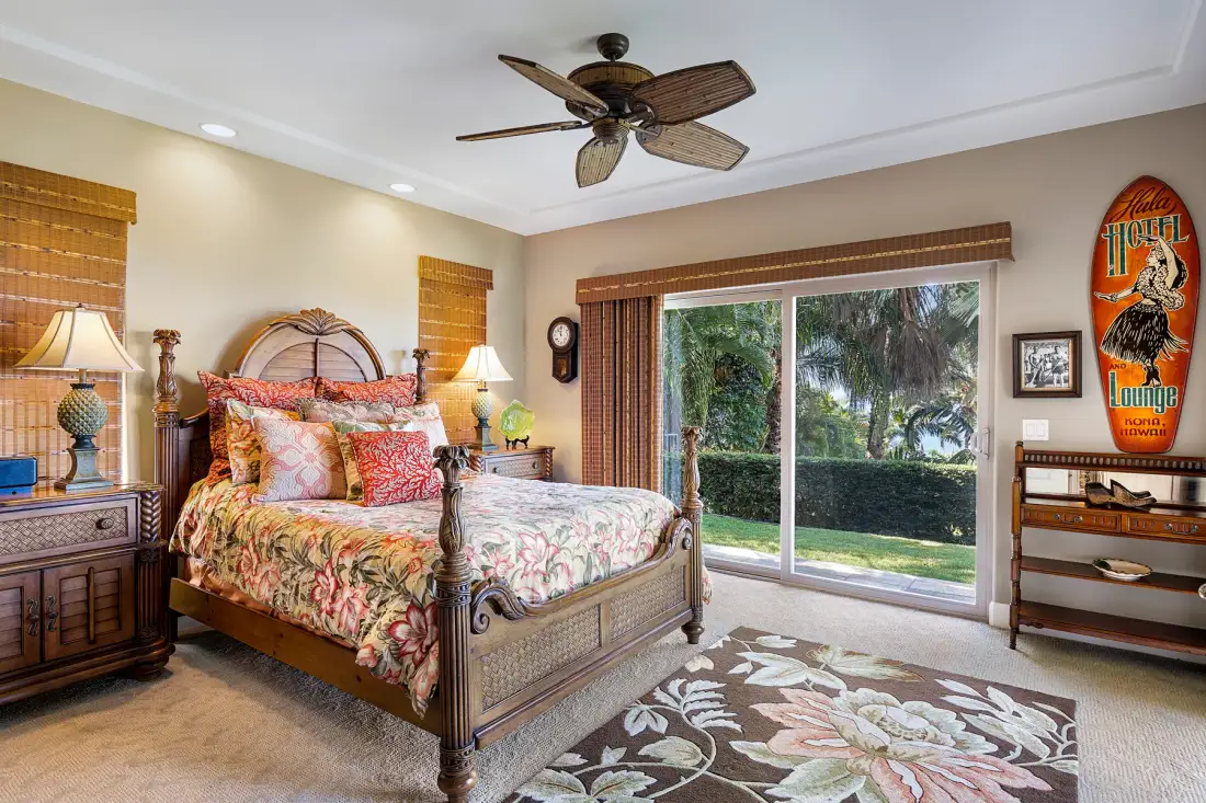 A bedroom with a bed beside a large sliding glass door opening onto a garden.