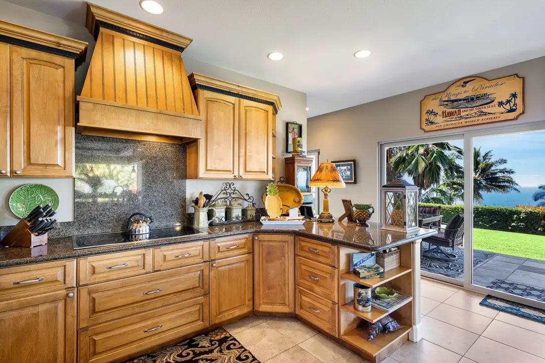 A kitchen with wooden cabinets and a countertop facing sliding glass doors.