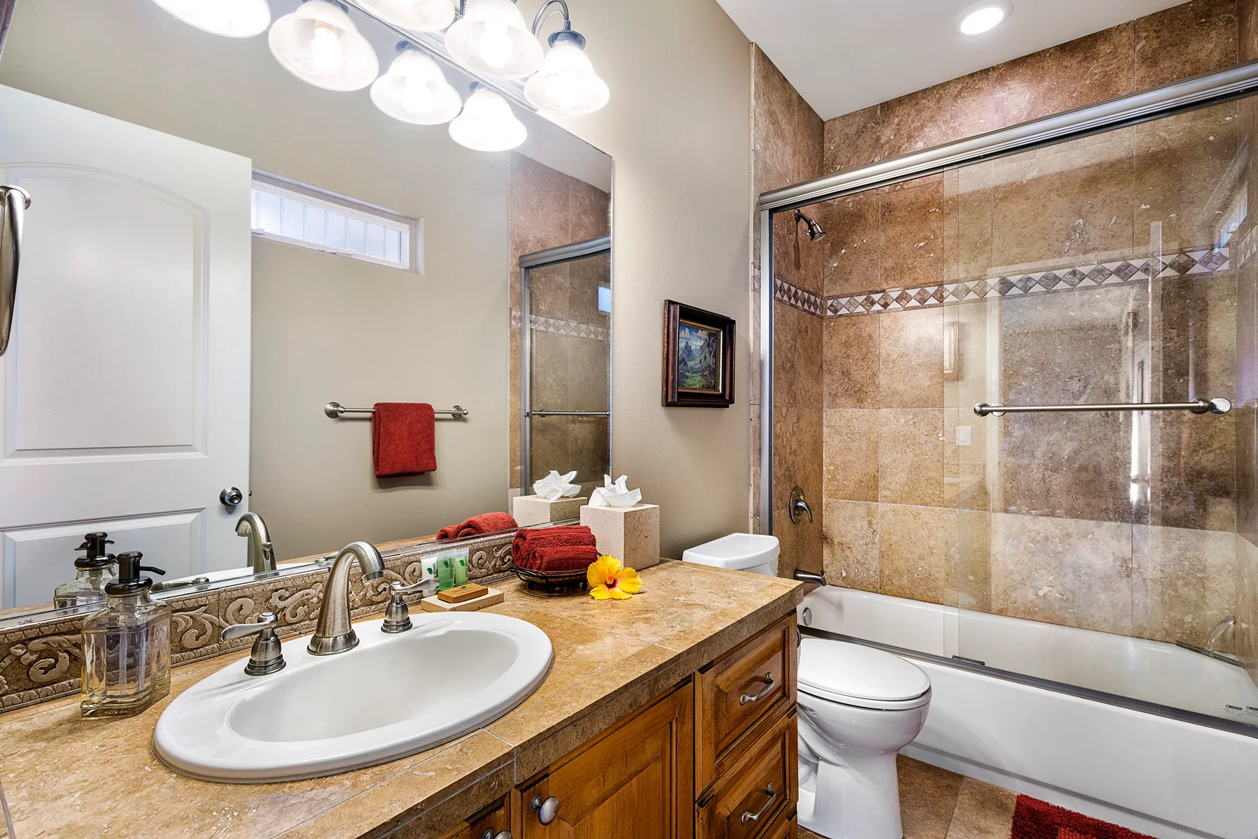 A bathroom with a sink vanity, toilet, and glass shower.