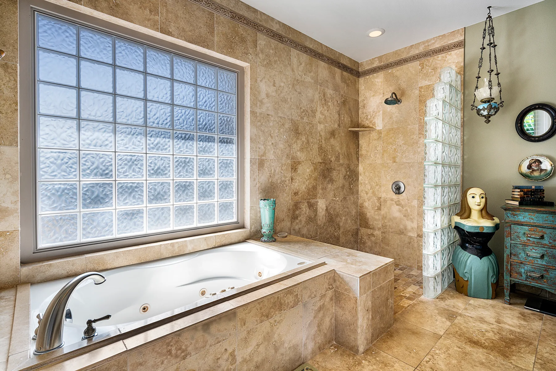 A tiled bathroom with a built-in tub and a large glass-block window.