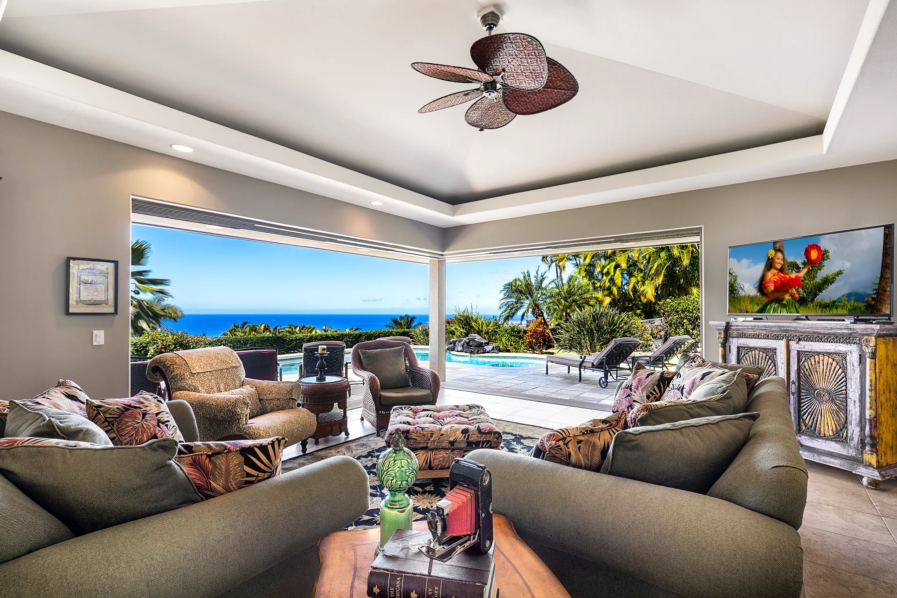 A living room opens onto a patio with a swimming pool and ocean views.