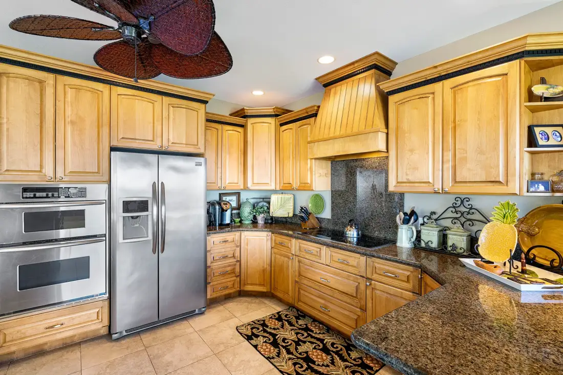 A kitchen with wooden cabinets, stainless steel appliances, and a stone countertop.