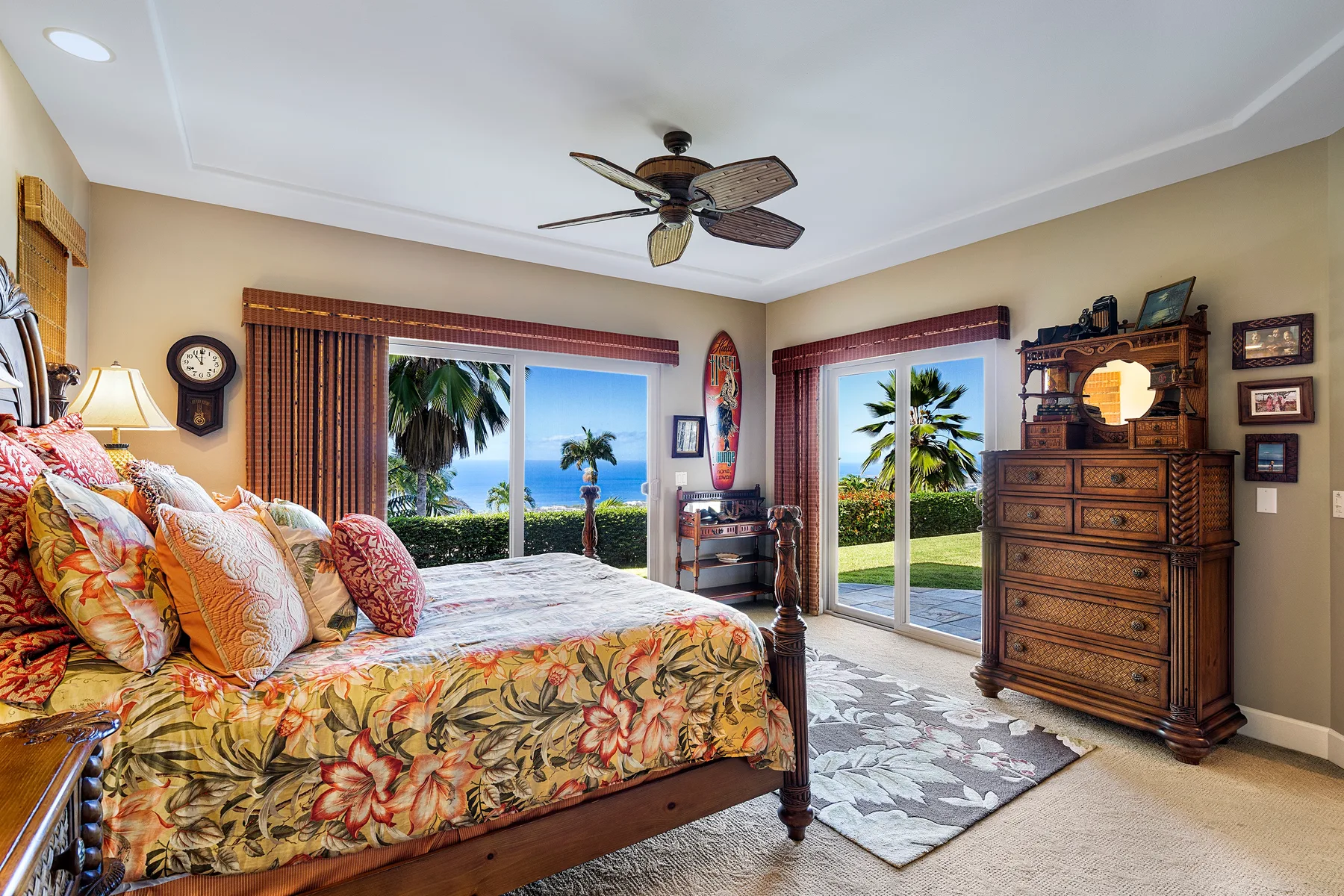 A bedroom with a floral bedspread and sliding glass doors opening onto palm trees.
