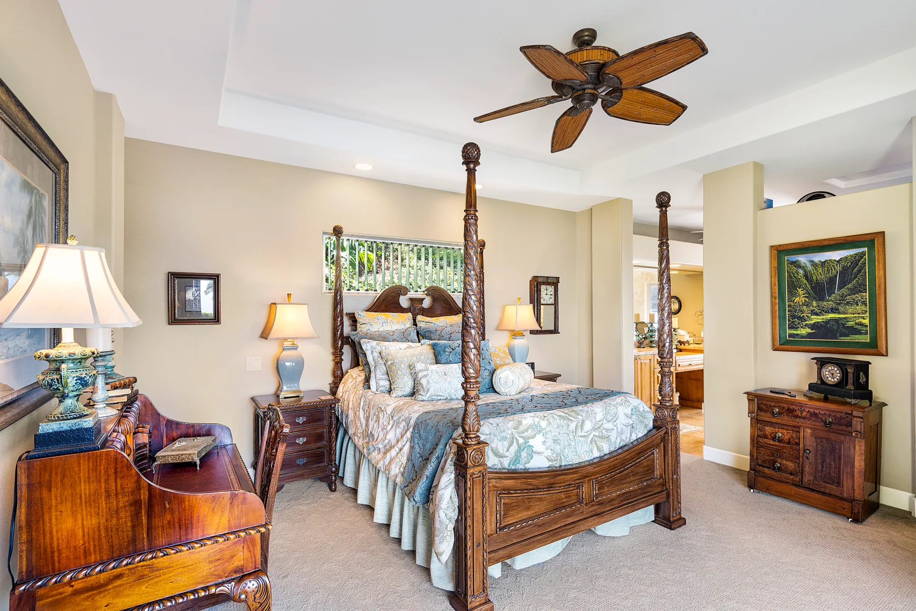 A bedroom with a carved wooden four-poster bed and ceiling fan.