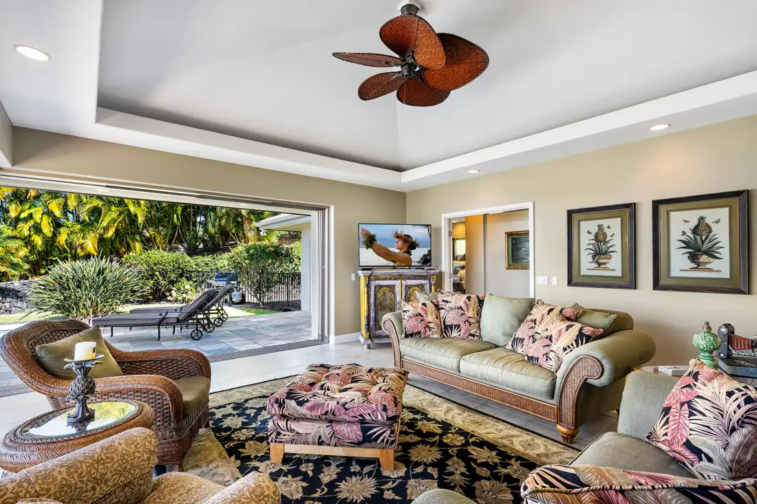 A living room with patterned seating and a large window overlooking greenery.
