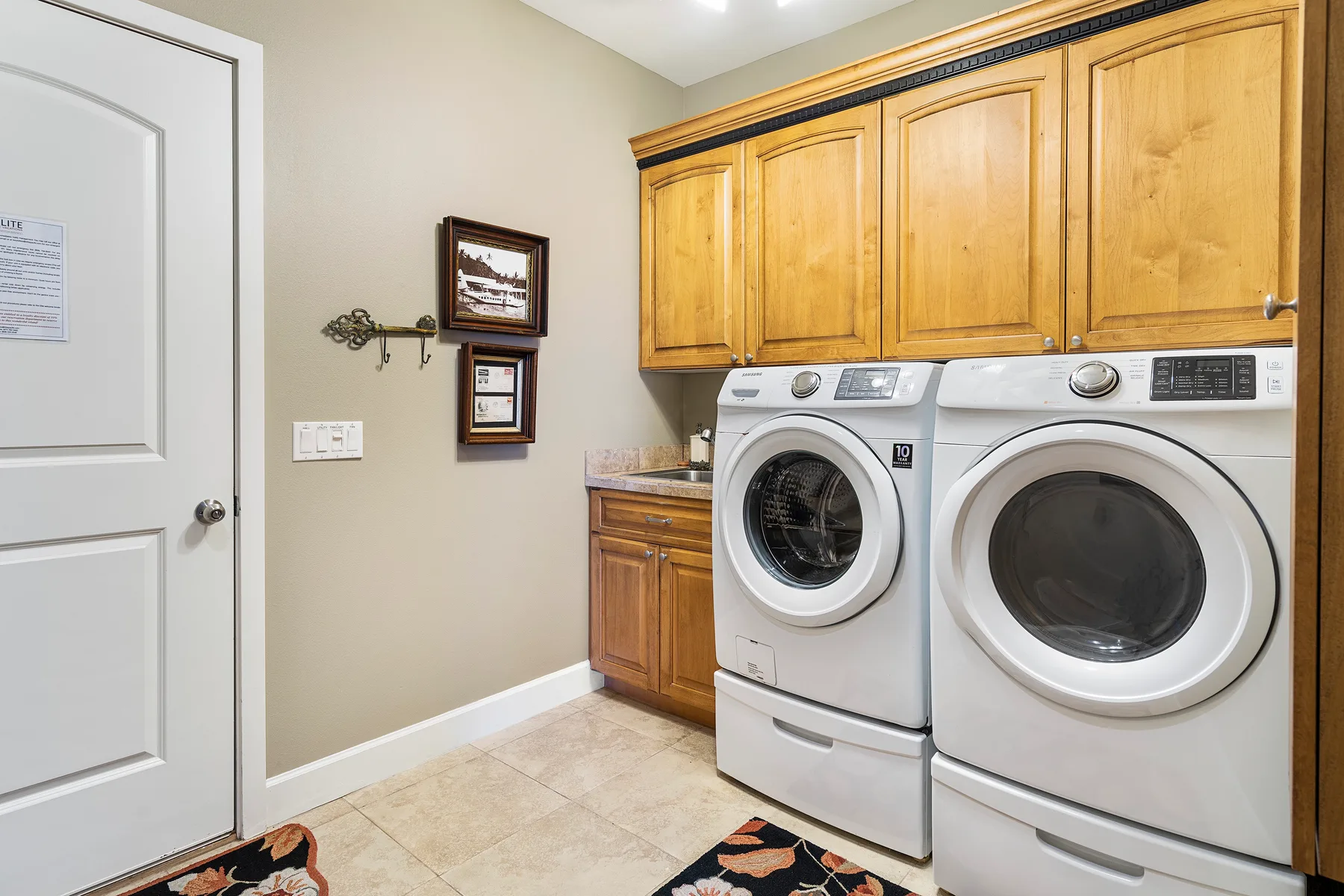 A laundry room with a washer and dryer beneath wooden cabinets.