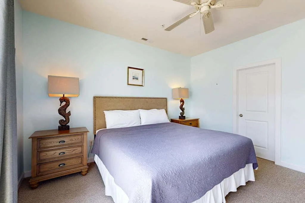 A bedroom with a bed, bedside tables, and a ceiling fan.