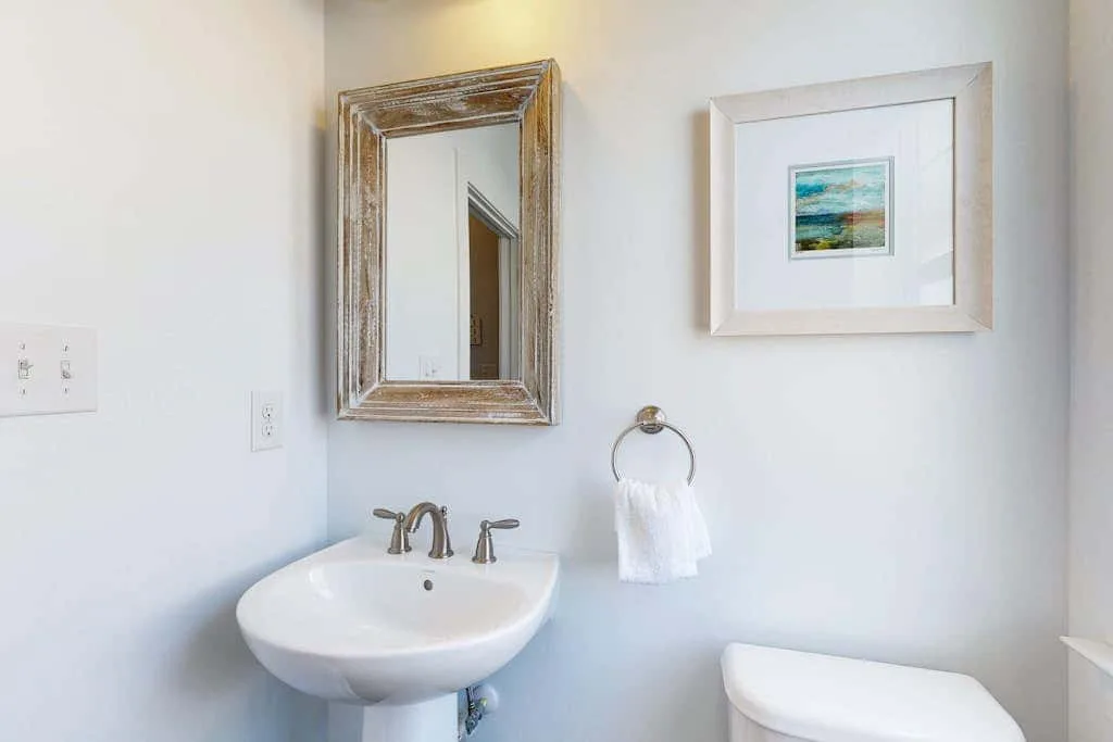 A bathroom vanity with a sink, mirror, and framed artwork.