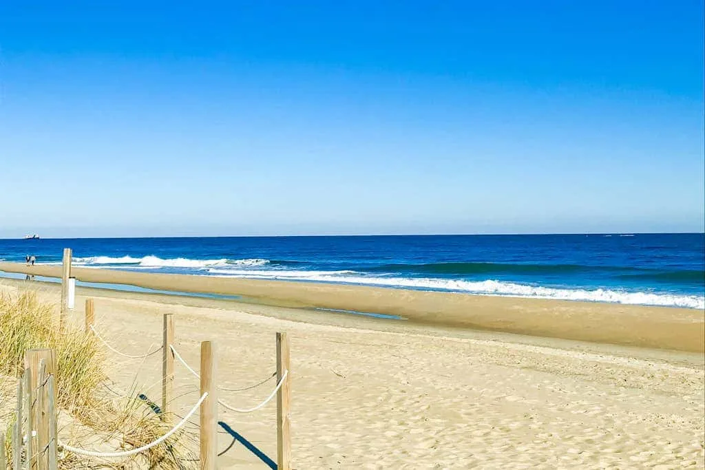 A sandy beach stretches along the ocean beneath a clear blue sky.