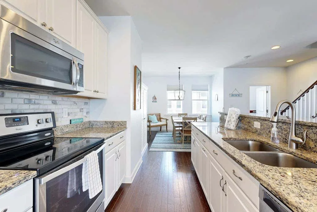 A bright kitchen with a long counter and a dining area beyond.