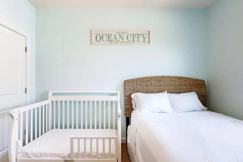 A bedroom with a crib beside a bed and a pale blue wall.